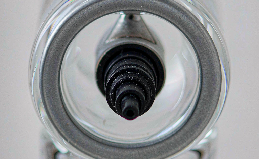 Close-up of perfume bottle neck showing crimp pump reducer insert and spray mechanism