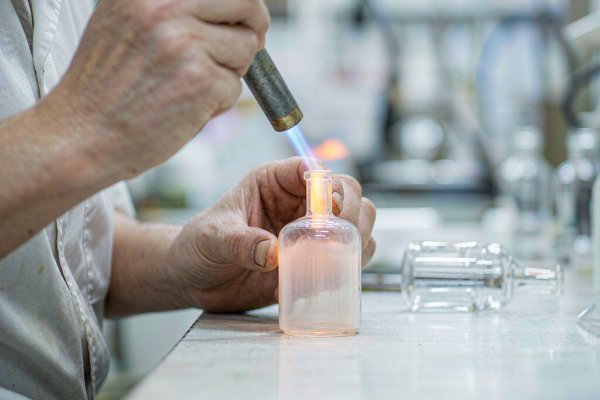 Fire polishing the neck of a glass perfume bottle with a gas flame