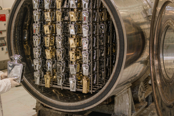 Vacuum metallization chamber with chrome and gold perfume bottles on rotating racks